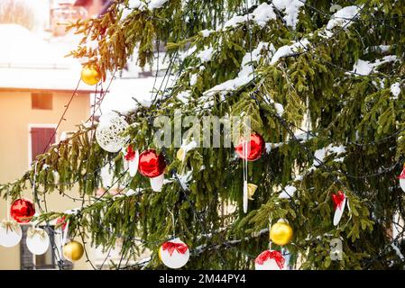 Particolare dell'albero di Natale all'aperto coperto di neve in una piazza della città in montagna Foto Stock