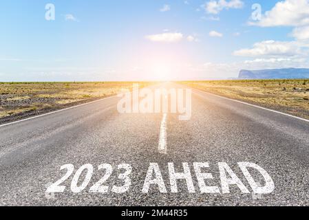 Nuovo anno 2023. Concettuale strada diritta vuota in un paesaggio pianeggiante con la frase 2023 davanti dipinta su asfalto Foto Stock