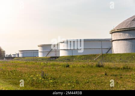 grandi serbatoi di petrolio greggio in un terminal petrolifero al tramonto Foto Stock