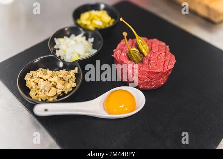 Tartare di manzo tradizionale su piatto nero. Uova crude e carne cruda nella cucina tradizionale polacca. Vista ad angolo alto. Foto di alta qualità Foto Stock