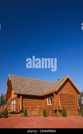 Casetta di legno marrone e rossastro con tetto di tegole di asfalto marrone e abbronzato in autunno. Foto Stock