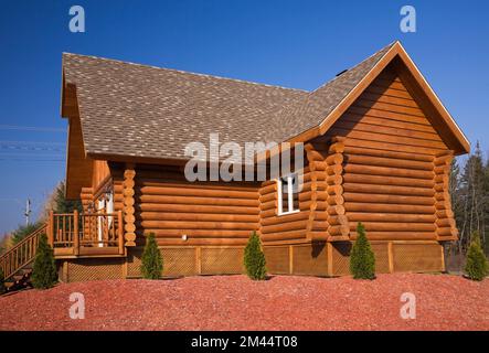 Casetta di legno marrone e rossastro con tetto di tegole di asfalto marrone e abbronzato in autunno. Foto Stock