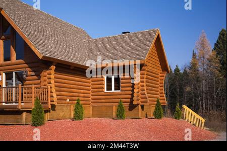 Casetta di legno marrone e rossastro con tetto di tegole di asfalto marrone e abbronzato in autunno. Foto Stock