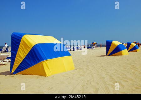 Le capanne di ombrello blu e gialle si allineano lungo Virginia Beach in una giornata di vacanza estiva per proteggere gli amanti della costa dal sole Foto Stock