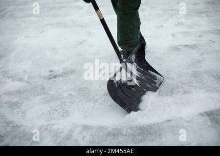 Pulizia della pala da neve. Neve in cortile in inverno. L'uomo pulisce il percorso dalle precipitazioni. Dettagli sulla pulizia della pala. Foto Stock