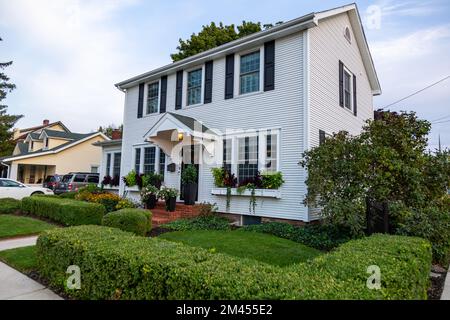 Una casa bianca a due piani circondata da cespugli verdi in un angolo a Auburn, Indiana, USA. Foto Stock