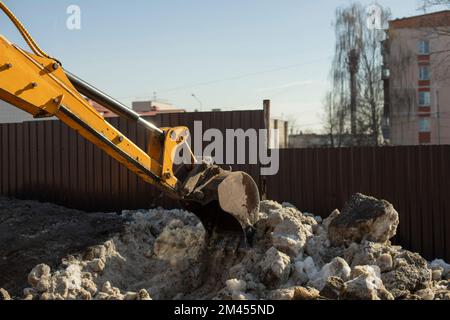 Rimozione della neve su strada. Ladle raccoglie la neve dal caus. La scala mobile pulisce i marciapiedi. Blocchi di ghiaccio in città. Foto Stock