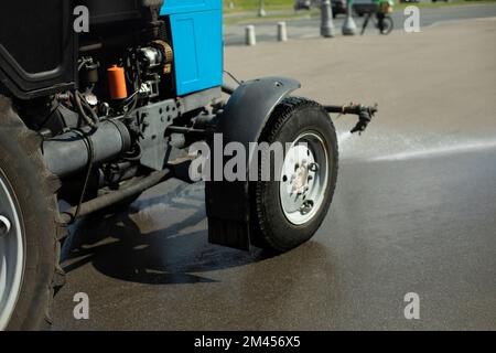 Autolavaggi strada. Il trattore versa l'acqua. Rimozione dello sporco dall'asfalto. Getto d'acqua dalla macchina. Pulizia della città. Foto Stock