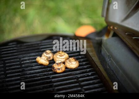 I funghi vengono grigliati. Dettagli picnic. Cibo su grata di acciaio. Cucina in estate. Foto Stock