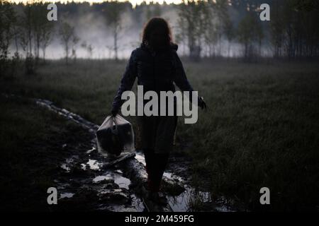 La ragazza cammina nella nebbia al mattino. Riposa in natura. Nebbia nella palude. L'uomo porta le cose all'acqua. Foto Stock