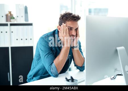 Le cose arent andando il suo senso oggi. un giovane uomo d'affari che guarda troppo stressato nel suo ufficio. Foto Stock