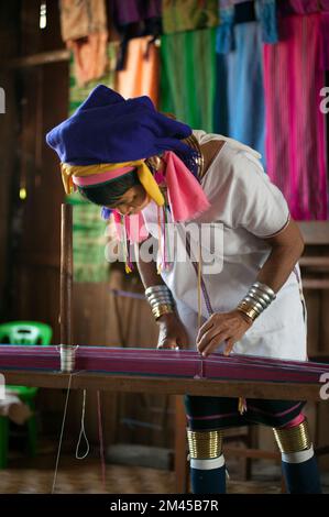 Due ragazze Padaung (Karen o Kayan Lahwi) che indossano gli anelli di metallo tradizionali intorno al suo collo, lavorando ad una tessitura in un villaggio galleggiante aperto., Myanmar. Foto Stock