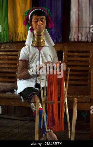 Due ragazze Padaung (Karen o Kayan Lahwi) che indossano gli anelli di metallo tradizionali intorno al suo collo, lavorando ad una tessitura in un villaggio galleggiante aperto., Myanmar. Foto Stock