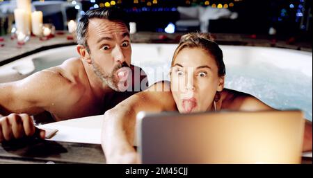 Divertitevi la nostra piccola vacanza. una coppia matura affettuosa che prende selfie sul loro tablet mentre si rilassa in una vasca idromassaggio. Foto Stock