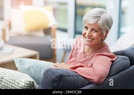 Shes pronto a fare la giornata. una donna matura allegra che si rilassa su un divano a casa. Foto Stock