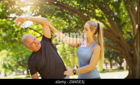 E ora ci allunghiamo di lato... un giovane istruttore che guida un uomo anziano in una lezione di yoga. Foto Stock