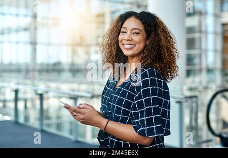 Sono in grado di connettersi facilmente con i miei clienti. Ritratto ritagliato di una giovane e attraente donna d'affari che utilizza uno smartphone in un ufficio moderno. Foto Stock