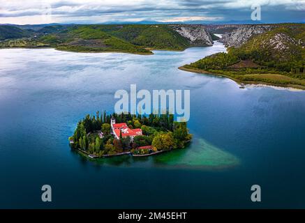 Visovac, Croazia - veduta aerea panoramica del monastero cristiano di Visovac nel Parco Nazionale di Krka in una mattinata estiva con le vette di Kijevski Kozjak An Foto Stock