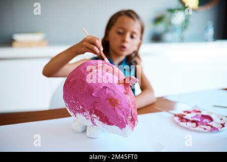 Piggy delizia. una adorabile bambina che lavora al suo progetto d'arte a casa. Foto Stock