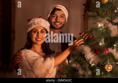 Ritratto di felice giovane coppia insieme decorando l'albero di Natale Foto Stock