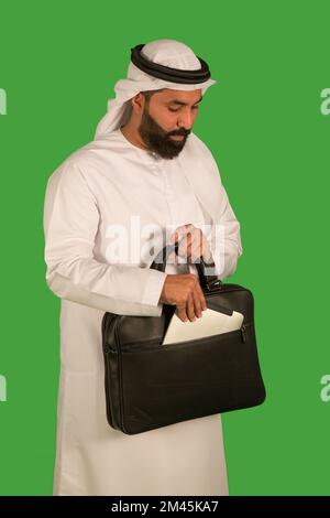 Uomo degli Emirati che estrae un tablet digitale dalla borsa. Foto Stock