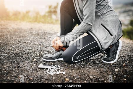 Preparati a correre il tuo cuore. Primo piano di una donna sportiva che legava le scarpe mentre si allenava all'aperto. Foto Stock