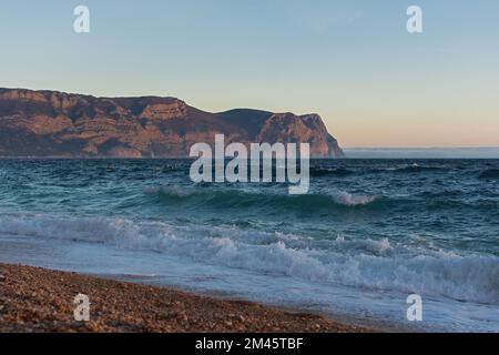 Serata di sabbia marina. Ora blu dopo il tramonto sul mare. Gli ultimi raggi del sole si riflettono nelle onde. Scivola di schiuma di mare sulla spiaggia. T Foto Stock