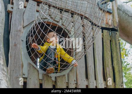 Un bambino sale su una griglia alpina in un parco giochi in una calda giornata estiva. parco giochi per bambini in un parco pubblico, intrattenimento e svago Foto Stock