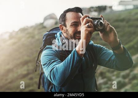 I momenti migliori sono sempre catturati nella mente e nel cuore. un uomo di mezza età che scatta foto con la fotocamera in montagna. Foto Stock