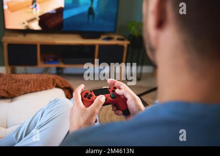 Figlio e padre giocano a videogame a casa, trascorrono del tempo insieme in famiglia, relazioni felici, intrattenimento online e attività ricreative Foto Stock