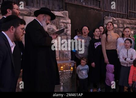 GERUSALEMME, ISRAELE - DICEMBRE 18: Il Rabbino Yitzchak Goldstein, Capo della Diaspora Yeshiva canta con la sua famiglia canzoni tradizionali Hanukkah dopo aver acceso una candela fuori casa la prima notte della festa ebraica di Hanukkah, a volte chiamata la festa delle luci, il 18 dicembre 2022 a Gerusalemme, Israele. Gli ebrei di tutto il mondo celebrano oggi il primo giorno di Hanukkah, il festival ebraico di otto giorni. Hanukkah, o Chanukah, commemora la vittoria ebraica nel 165 a.C. sull'oppressione siriano-greca guidata dal re Antioco IV Credit: Eddie Gerald/Alamy Live News Foto Stock