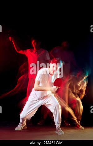 giovane uomo che gioca a ping pong in misto luce al neon Foto Stock