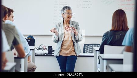 Istruzione, professore universitario e studenti in aula per lezioni sull'innovazione in scienza, fisica o matematica. Focus, attenzione e college donna Foto Stock