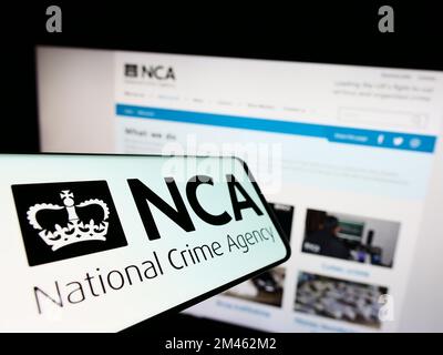 Telefono cellulare con il logo della British National Crime Agency (NCA) sullo schermo di fronte al sito web. Messa a fuoco al centro del display del telefono. Foto Stock