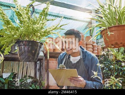 Pianta, vivaio e piccolo uomo di affari che scrive sulla lista di controllo di qualità, la crescita e lo sviluppo in un negozio di giardinaggio con le piante del POT. Maschio Foto Stock