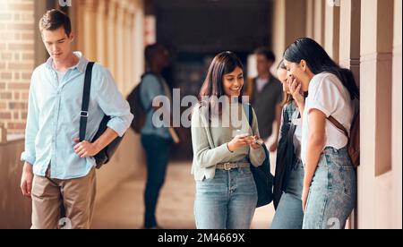 Università, corridoio e gruppo di studenti con telefono ridere di social media, internet e meme online. Educazione, comunicazione e amici Foto Stock