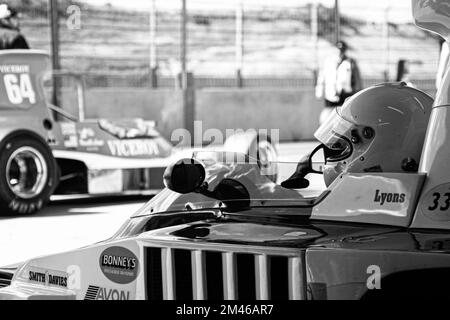 Foto di un autista che indossa un casco di sicurezza, seduto in una auto da corsa Lola 332 d'epoca. Foto Stock