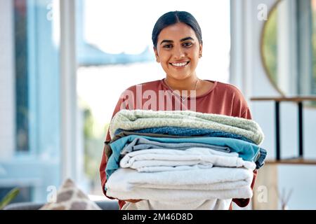 Ritratto, pulizia o donna con lavanderia o sorriso felice dopo il lavaggio di vestiti o asciugamani in servizi di pulizia. Ospitalità, hotel o faccia di indiano Foto Stock