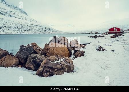 Rocce su una riva nevosa paesaggio fluviale foto Foto Stock