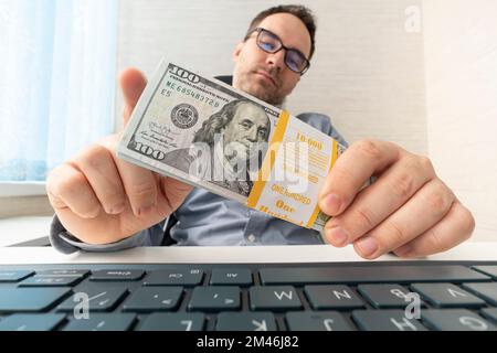 Uomo d'affari in possesso di dollari. Concetto di corruzione. Un uomo in ufficio conta i soldi che ha guadagnato. Profitto dal commercio in linea. adorazione gioiosa Foto Stock