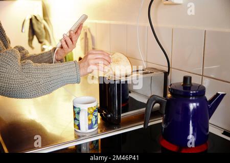 Donna che mette le fette di pane nel tostapane Foto Stock