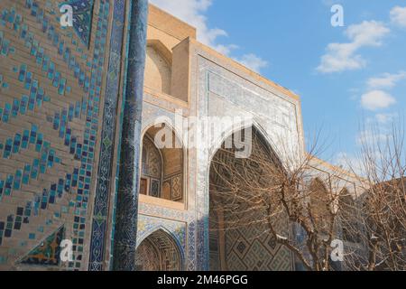 Il sole si riflette sulla facciata di un'antica madrasa con un motivo piastrellato blu orientale. Piazza Registan. Samarcanda Foto Stock