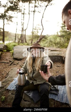 Donna sorridente che tiene thermos Foto Stock