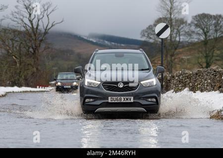 Yorkshire Dales, Regno Unito, 19 dic 2022 - Meteo - inondazioni in flash dopo il rapido scongelamento ha visto il viaggio interrotto intorno alle Yorkshire Dales, in quanto il terreno congelato non è stato in grado di assorbire le acque scioglienti della neve. Questi veicoli hanno lottato attraverso l'acqua in aumento mentre viaggiavano verso Hawes nello Yorkshire Dales, Regno Unito. Credit: Wayne HUTCHINSON/Alamy Live News Foto Stock