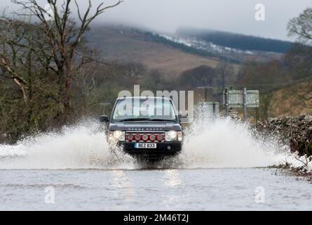 Yorkshire Dales, Regno Unito, 19 dic 2022 - Meteo - inondazioni in flash dopo il rapido scongelamento ha visto il viaggio interrotto intorno alle Yorkshire Dales, in quanto il terreno congelato non è stato in grado di assorbire le acque scioglienti della neve. Questi veicoli hanno lottato attraverso l'acqua in aumento mentre viaggiavano verso Hawes nello Yorkshire Dales, Regno Unito. Credit: Wayne HUTCHINSON/Alamy Live News Foto Stock