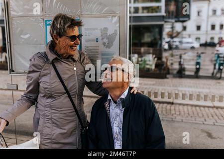 Coppia anziana in attesa alla fermata dell'autobus Foto Stock