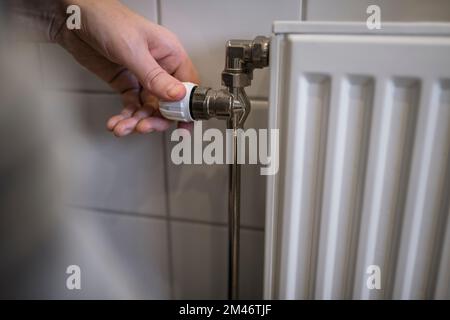 Persona che accende il termostato sul radiatore Foto Stock