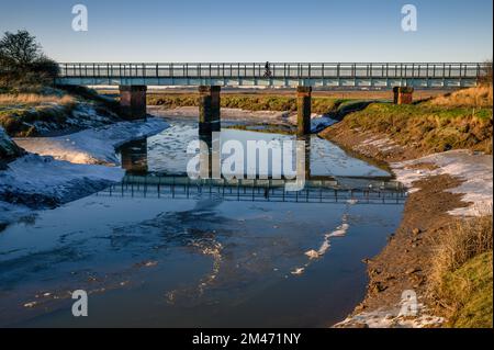 Il fiume congelato Conder passa sotto un ponte ferroviario in disuso a Conder Green vicino a lancaster Foto Stock