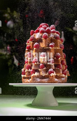 Lampone di Natale decorato Pandoro dolce italiano (pan d'oro) spolverato con zucchero a velo su fondo verde Foto Stock