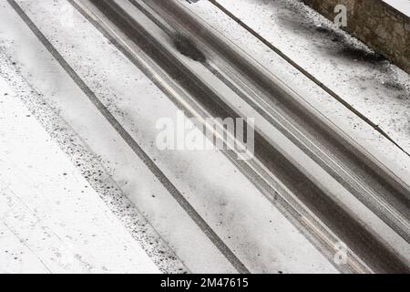 Cingoli di pneumatici su una strada innevata durante le nevicate Foto Stock